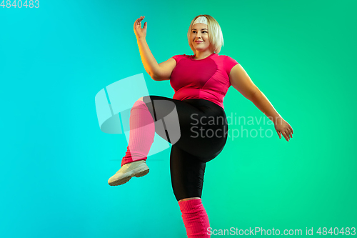 Image of Young caucasian plus size female model\'s training on gradient green background