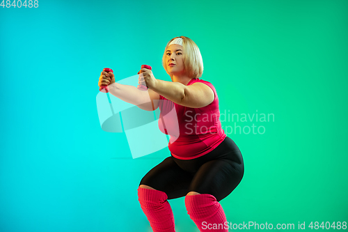 Image of Young caucasian plus size female model\'s training on gradient green background