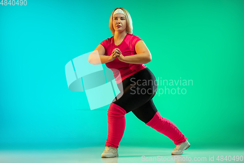 Image of Young caucasian plus size female model\'s training on gradient green background