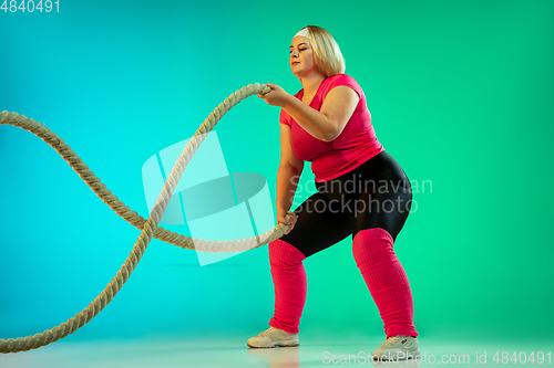 Image of Young caucasian plus size female model\'s training on gradient green background