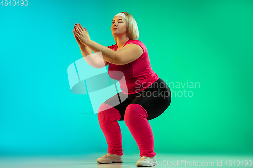 Image of Young caucasian plus size female model\'s training on gradient green background