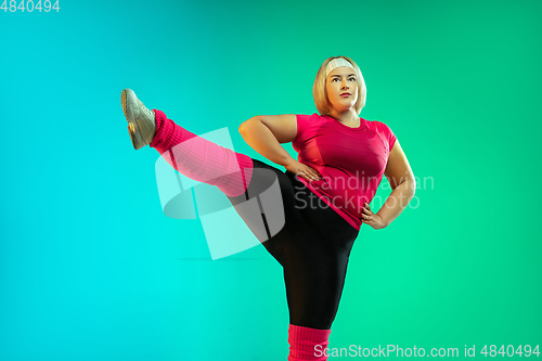 Image of Young caucasian plus size female model\'s training on gradient green background