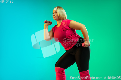 Image of Young caucasian plus size female model\'s training on gradient green background