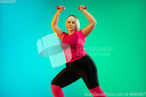 Image of Young caucasian plus size female model\'s training on gradient green background