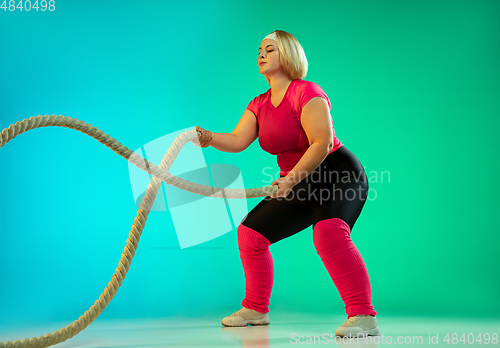 Image of Young caucasian plus size female model\'s training on gradient green background