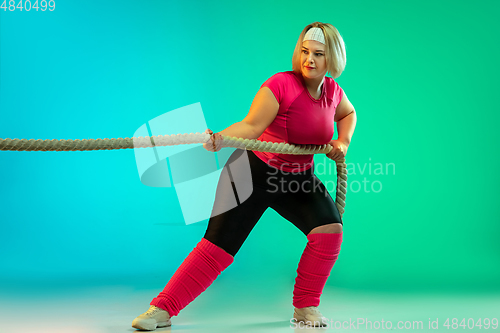 Image of Young caucasian plus size female model\'s training on gradient green background