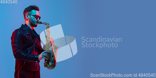 Image of Young caucasian jazz musician playing the saxophone in neon light, flyer