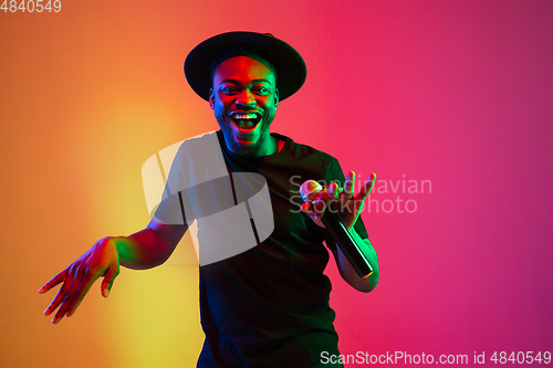 Image of Young african-american musician singing, dancing in neon light