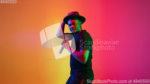 Image of Young african-american musician singing, dancing in neon light