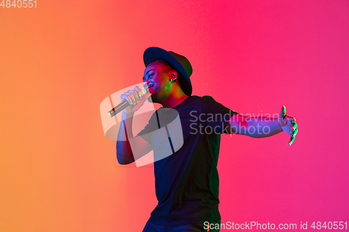 Image of Young african-american musician singing, dancing in neon light