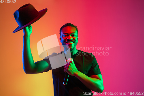 Image of Young african-american musician singing, dancing in neon light