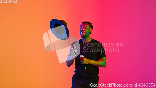 Image of Young african-american musician singing, dancing in neon light, flyer