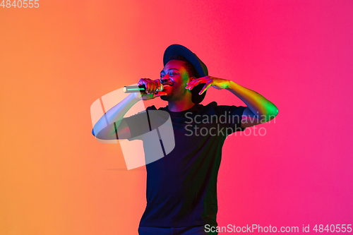 Image of Young african-american musician singing, dancing in neon light