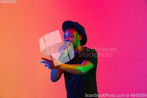 Image of Young african-american musician singing, dancing in neon light