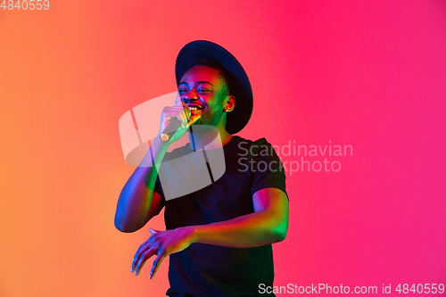 Image of Young african-american musician singing, dancing in neon light