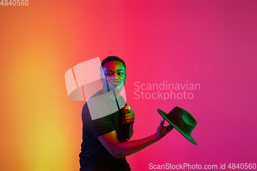 Image of Young african-american musician singing, dancing in neon light