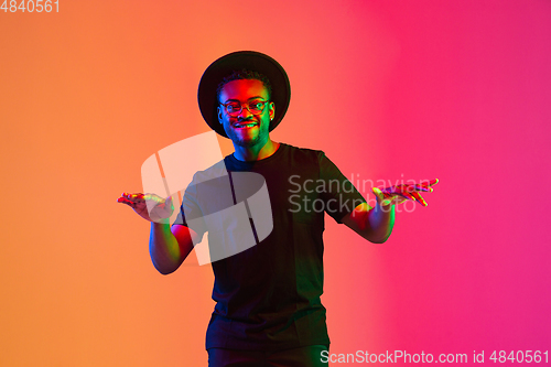 Image of Young african-american musician singing, dancing in neon light