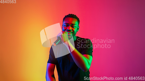 Image of Young african-american musician singing, dancing in neon light