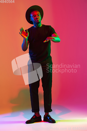 Image of Young african-american musician singing, dancing in neon light