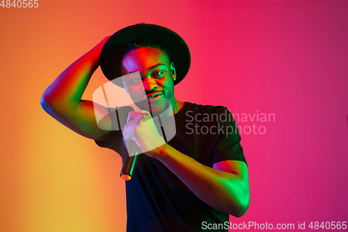 Image of Young african-american musician singing, dancing in neon light