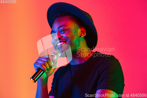 Image of Young african-american musician singing, dancing in neon light