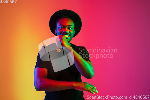 Image of Young african-american musician singing, dancing in neon light