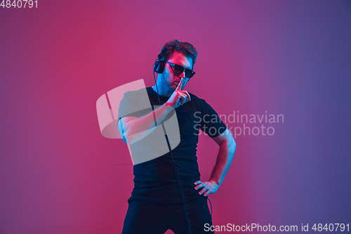 Image of Young caucasian musician singing, dancing in neon light