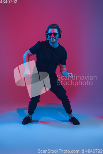 Image of Young caucasian musician singing, dancing in neon light