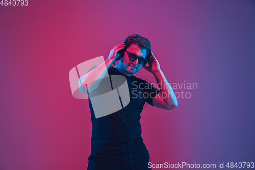 Image of Young caucasian musician singing, dancing in neon light