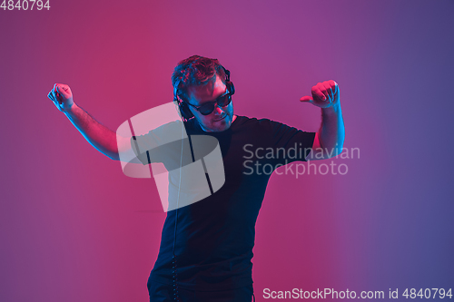 Image of Young caucasian musician singing, dancing in neon light