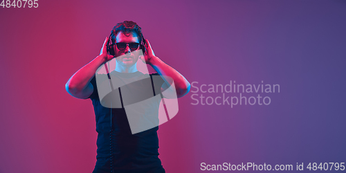 Image of Young caucasian musician singing, dancing in neon light, flyer