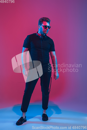 Image of Young caucasian musician singing, dancing in neon light
