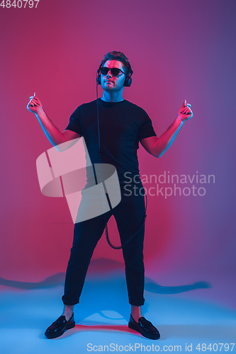 Image of Young caucasian musician singing, dancing in neon light