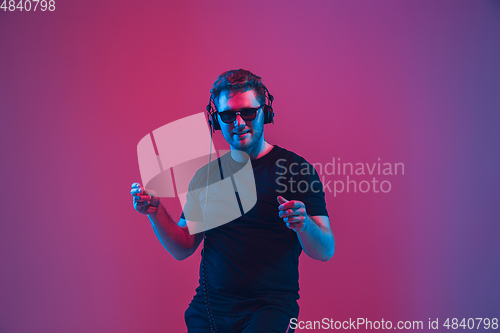Image of Young caucasian musician singing, dancing in neon light