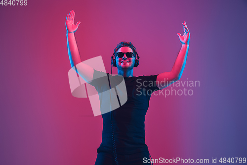 Image of Young caucasian musician singing, dancing in neon light