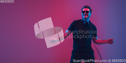 Image of Young caucasian musician singing, dancing in neon light, flyer