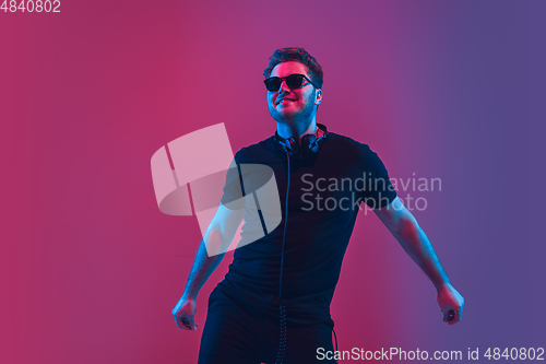 Image of Young caucasian musician singing, dancing in neon light