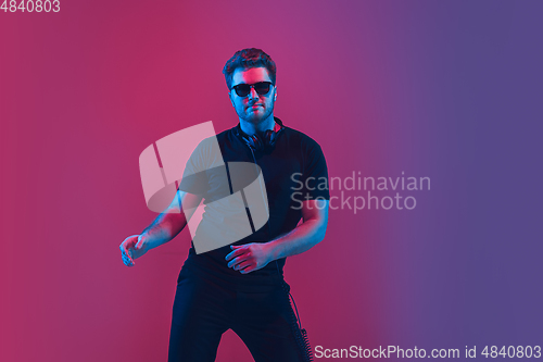 Image of Young caucasian musician singing, dancing in neon light