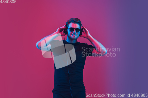 Image of Young caucasian musician singing, dancing in neon light