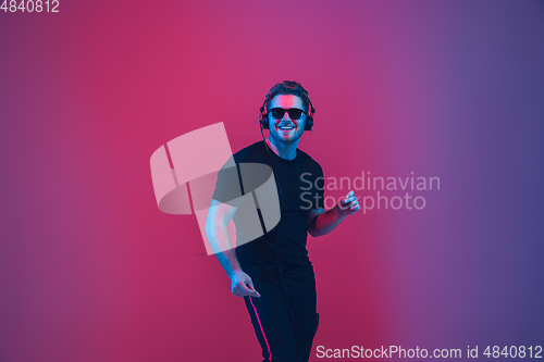 Image of Young caucasian musician singing, dancing in neon light