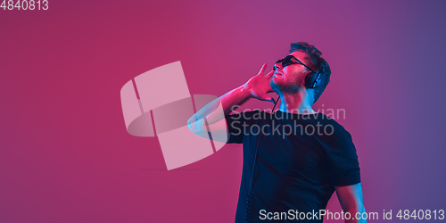 Image of Young caucasian musician singing, dancing in neon light, flyer