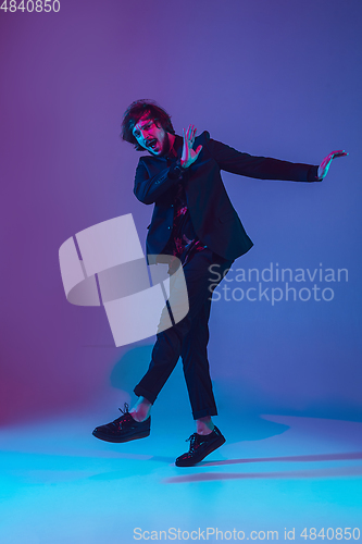 Image of Young caucasian musician dancing in neon light