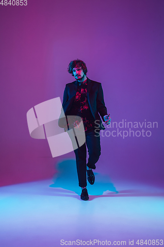 Image of Young caucasian musician dancing in neon light