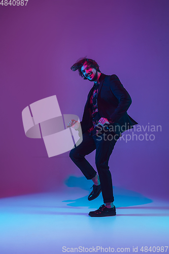 Image of Young caucasian musician dancing in neon light