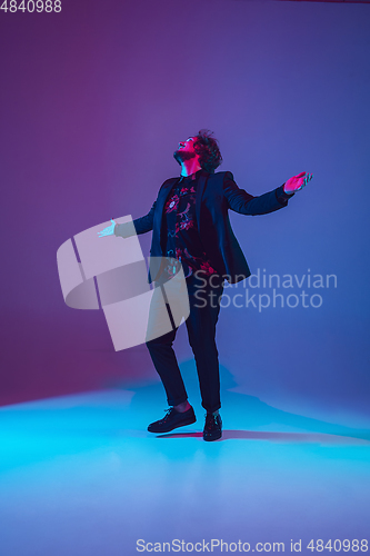 Image of Young caucasian musician dancing in neon light