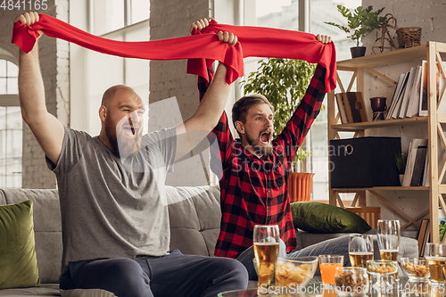 Image of Excited, happy friends watch sport match together on the couch at home