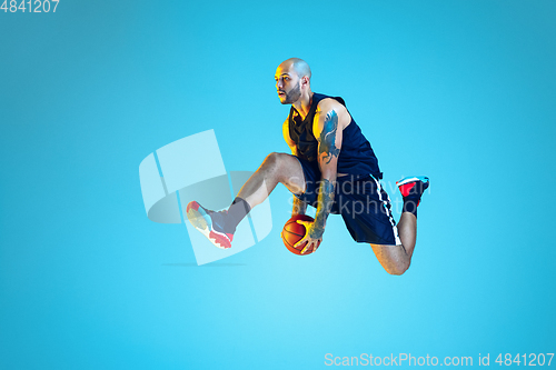 Image of Young basketball player training isolated on blue studio background in neon light