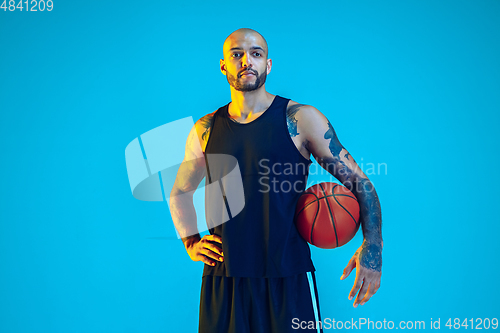 Image of Young basketball player training isolated on blue studio background in neon light