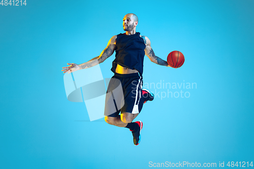 Image of Young basketball player training isolated on blue studio background in neon light