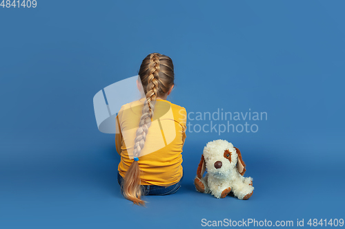 Image of Portrait of sad little girl sitting on blue studio background, autism concept